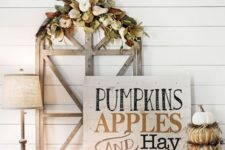 a chic whitewashed wooden sign with black and rust-colored letters, pumpkins and candles around
