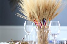 a clear jar with wheat wrapped with colorful twine is a bold and fun fall centerpiece to try