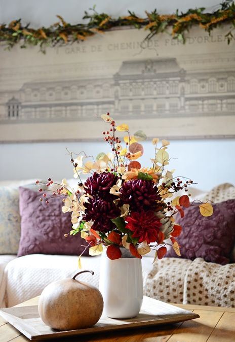 a colorful fall arrangement of leaves, branches with berries, faux bright blooms and a large veggie next to it