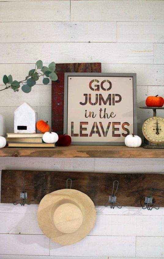 a contemporary fall sign with letters in bright orange and lots of fabric pumpkins around