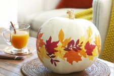 a cool pumpkin centerpiece with bright fall leaves attached is an amazing fall decoration