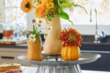 a cool rustic decoration of a metal stand with gourds and pumpkins plus greenery and faux bright blooms