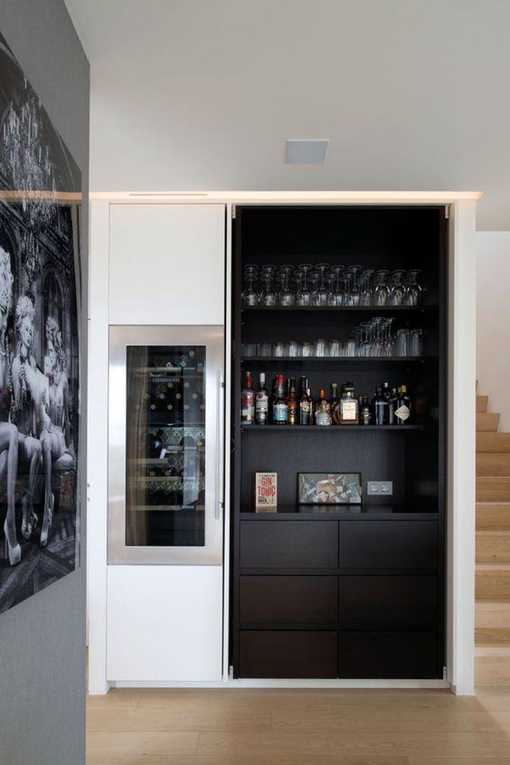 A dark built in home bar with open shelves, artworks and sleek drawers is very stylish and chic