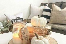 a fall arrangement of a wood slice, vintage books, faux pumpkins and a candle in a jar is very easy and cool