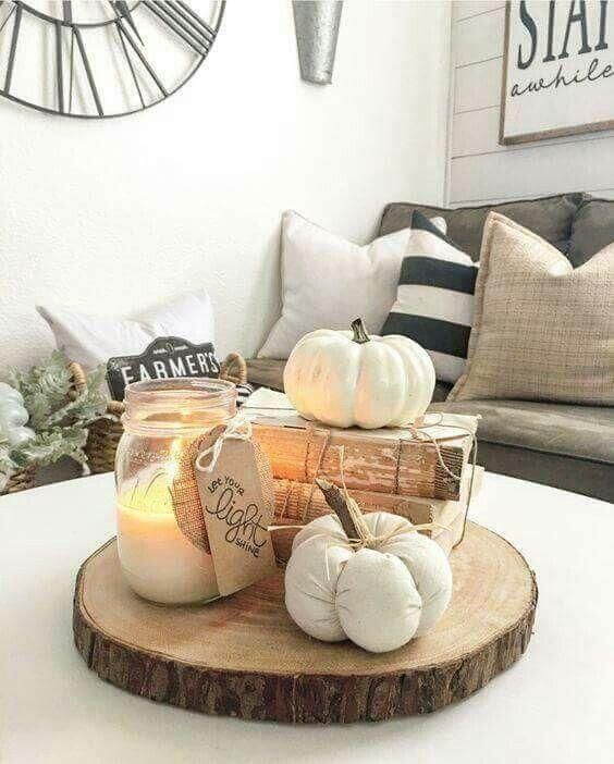 a fall arrangement of a wood slice, vintage books, faux pumpkins and a candle in a jar is very easy and cool