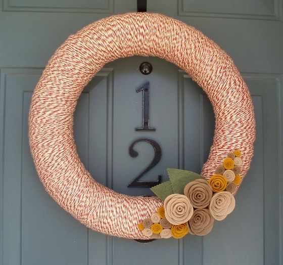 a fall wreath covered with colorful yarn with neutral fabric blooms and leaves is easy to make yourself