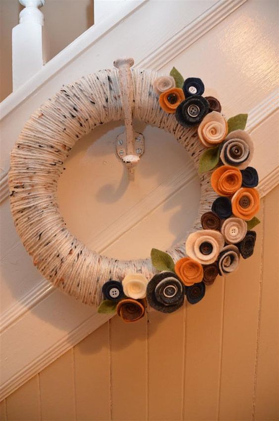a fall wreath covered with neutral yarn, with fabric flowers with buttons is a cool idea