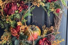 a fall wreath of leaves, faux bright blooms, pumpkins and twigs of various kinds is very chic