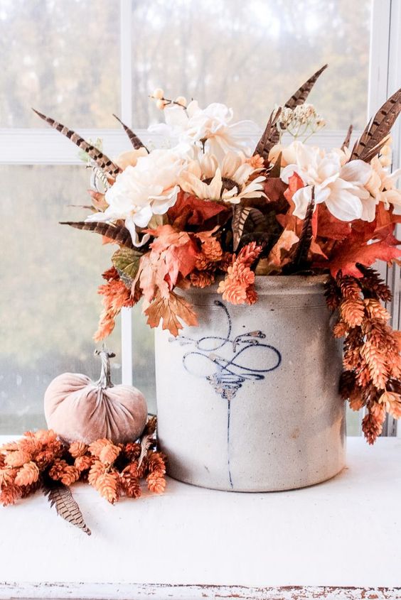 a fantastic fall boho centerpiece of white blooms, fall leaves, feathers in a bucket is a very bold and chic idea