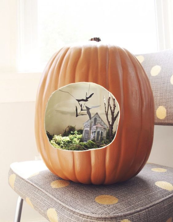 A faux pumpkin with a Halloween scene   moss, a mini house, tree and blackbirds for Halloween