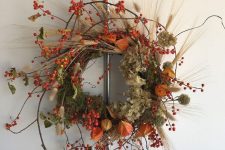 a gorgeous lush fall wreath with twigs, berries, dried blooms, leaves and wheat is lovely and bright