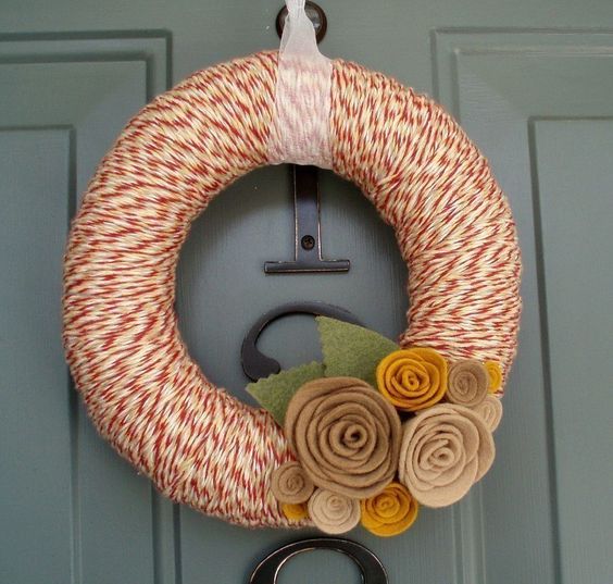 a moody fall wreath with red and white yarn, neutral fabric flowers and leaves is a cool idea for decorating