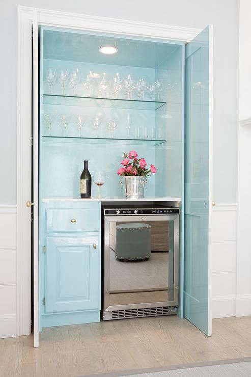a pastel blue home bar with open glass shelves, a built-in light, a fridge and a cabinet is very romantic