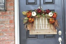 a reclaimed wood sign with fake blooms, leaves and veggies for accentign your front door in the fall