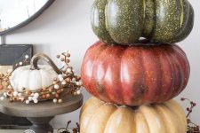 a rustic decoration – a stack of colored fall pumpkins plus a wreath of berries and acorns is a lovely idea for the fall