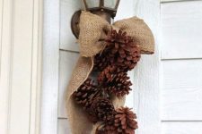 a rustic posie of pinecones and a burlap bow is a cool decoration for your front door or any other space