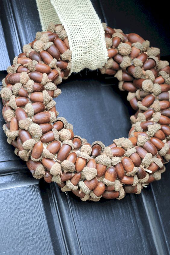 a simple and cool acorn wreath with a burlap ribbon is a lovely idea for a rustic outdoor space