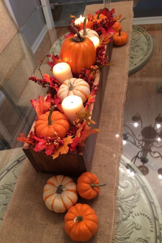 a simple fall centerpiece of a wooden box, with faux leaves, berries, pumpkins and pillar candles