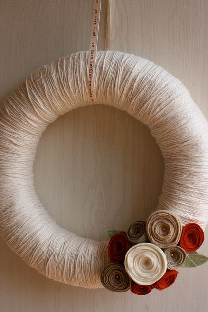a simple fall wreath covered with neutral yarn and with bright fabric blooms and leaves is a fast DIY