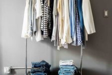 a simple metal clothes rack on casters with lots of hangers and compartments for storage in the lower part