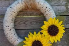 a simple summer to fall wreath covered with neutral yarn and with faux sunflowers of fabric and leaves