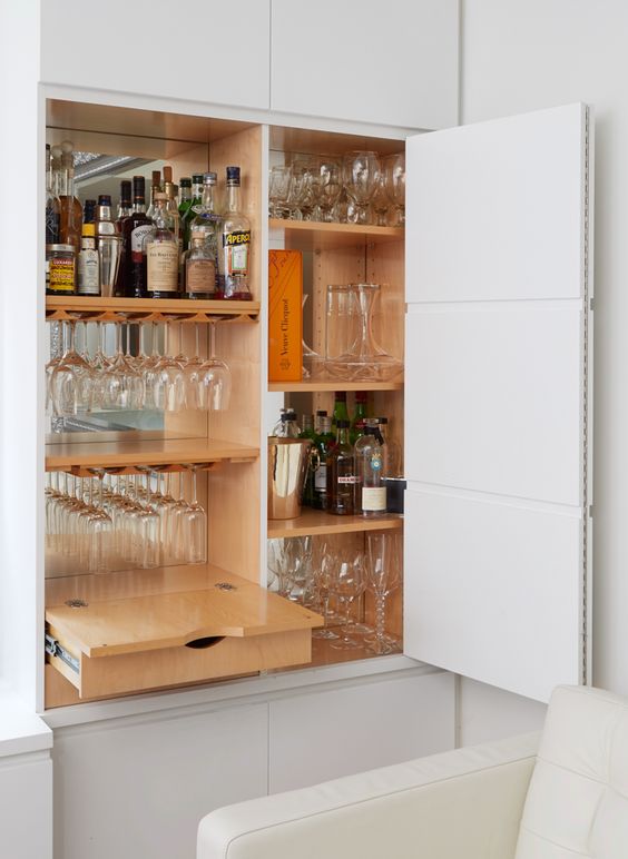 A small built in home bar with a mirror backsplash, a drawer and shelves is a cool idea to save some space