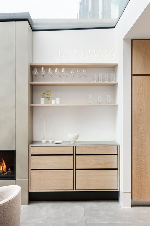 a small built-in home bar with open shelves, sleek drawers and candles is a chic addition to your living room