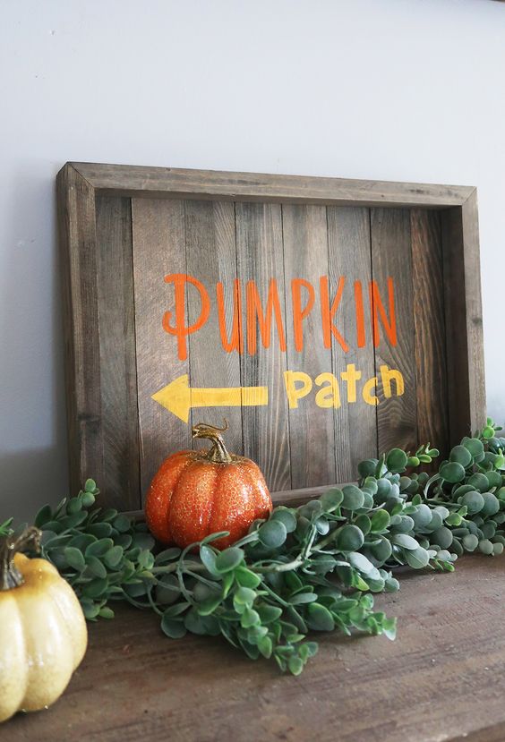 a stained fall sign with colorful letters, fresh greenery and colorful faux pumpkins