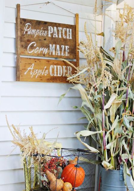a stained wooden sign with white letters and a wire basket with fall veggies and greenery for a fall touch