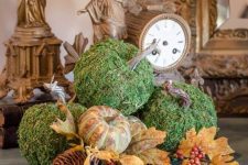 a stylish rustic fall arrangement of moss pumpkins, faux leaves, pumpkins of plastic, berries and pinecones for a woodland or rustic feel