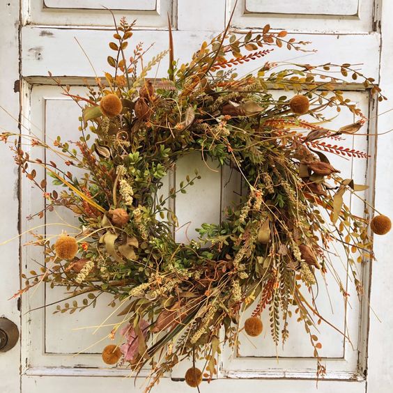 a super textural fall wreath with twigs, fall foliage, billy balls, grasses and some wildflowers is a cool fall decoration