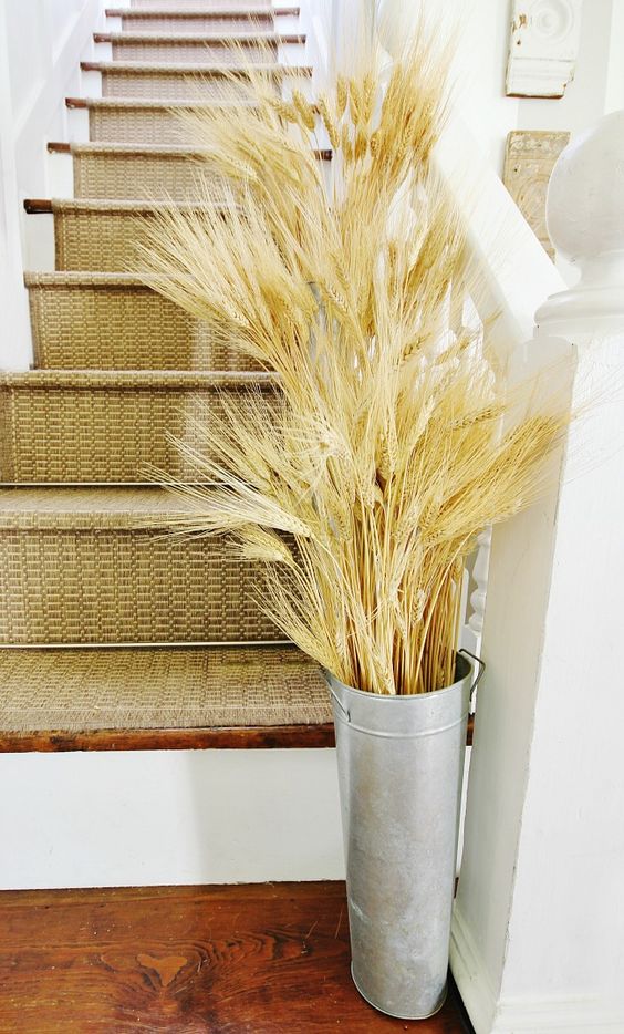 a tall and thin bucket with lots of wheat placed at the stairs to accent this zone and bring a fall feel to the space