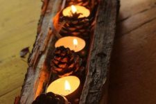 a tree stump with pinecones and tealights is a cool rough rustic centerpiece that will scream fall