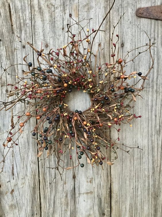 a twig fall wreath with dried leaves and berries looks catchy and will be a fit for fall or Halloween