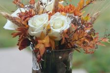 a vase with pebbles and rocks, dried fall leaves, white roses, wheat looks very chic and very natural
