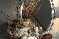 a vintage rustic decoration with lots of neutral pumpkins with berries, green hydrangeas and twigs and sticks