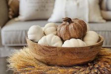 a wheat wreath surrounding a wooden bowl with white pumpkins and a wooden one for the fall