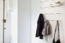 a white wall with lot sof hooks to hang clothes and bags or even place shelves and store shoes on them