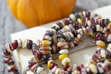 an Indian corn seed garland is a bright and all-natural decor idea for fall and Thanksgiving, looks chic and nice