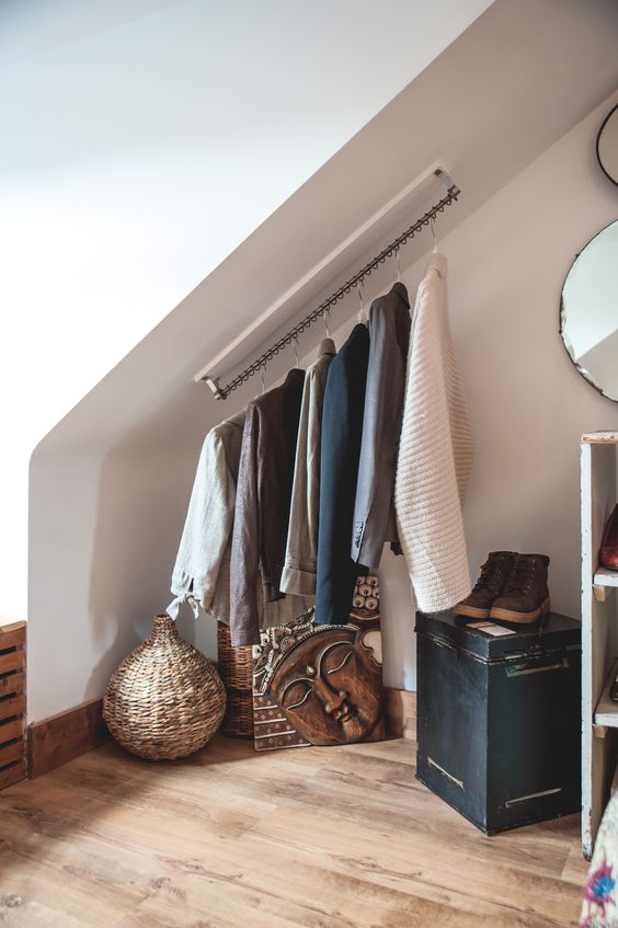 an attic space with a holder for clothes hangers attached right to the ceiling is a great way to save some space
