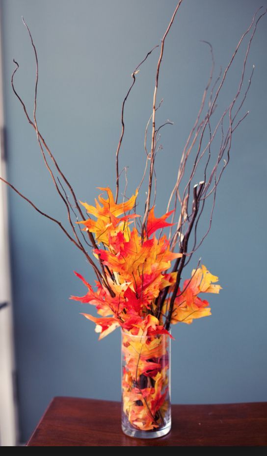 An easy and budget friendly fall centerpiece of twigs and bright faux leaves in a vase to make last minute