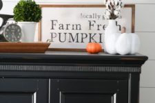 an elegant framed monochromatic sign in a stained wooden frame, some cotton and fake pumpkins