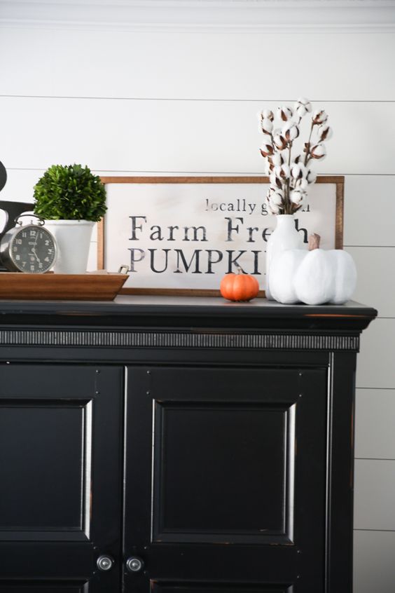 an elegant framed monochromatic sign in a stained wooden frame, some cotton and fake pumpkins
