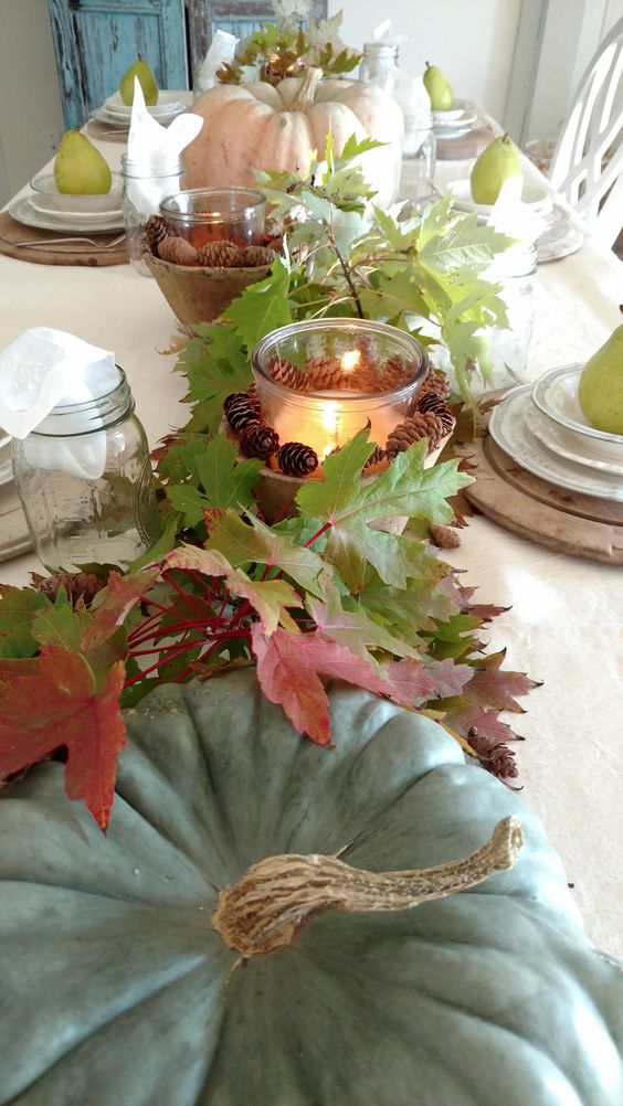 fall table decor with heirloom pumpkins, fall leaves, candle lanterns with pinecones is very cozy