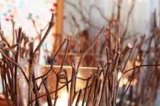 square glass candleholders covered with twigs and sticks are cool decorations that bring coziness to the space