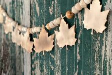 such a natural fall garland can be made of wooden beads and leaves, and it looks cozy and stylish in fall and Thanksgiving spaces