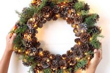 such a pinecone, evergreens and lights wreath can be a nice decoration from fall to winter and is easy to make