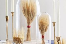 wheat bundles with red twine in cloches and on wooden stands, with candles and candle holders with wheat for fall