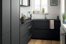 a Scandinavian kitchen with white walls, matte black cabinets and built-in appliances, a gold pendant lamp and accessories