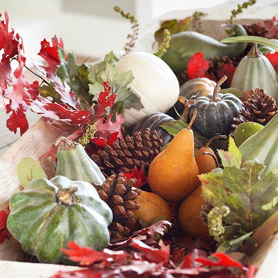 a Thanksigiving centerpiece of faux pumpkins and gourds, pears and leaves plus pinecones